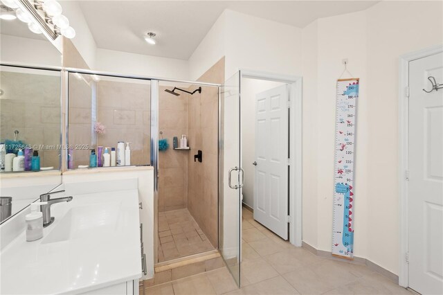 bathroom featuring a shower with shower door, sink, and tile patterned floors