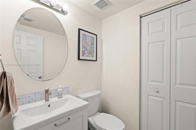 bathroom with tasteful backsplash, toilet, and vanity