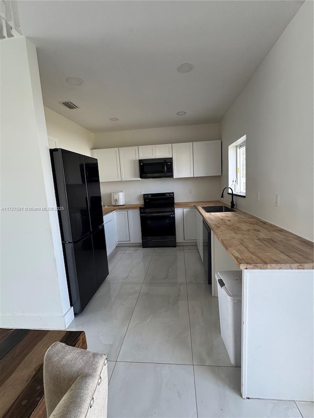 kitchen featuring black appliances, white cabinets, wooden counters, and sink