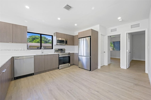 kitchen with light wood-type flooring, appliances with stainless steel finishes, and sink