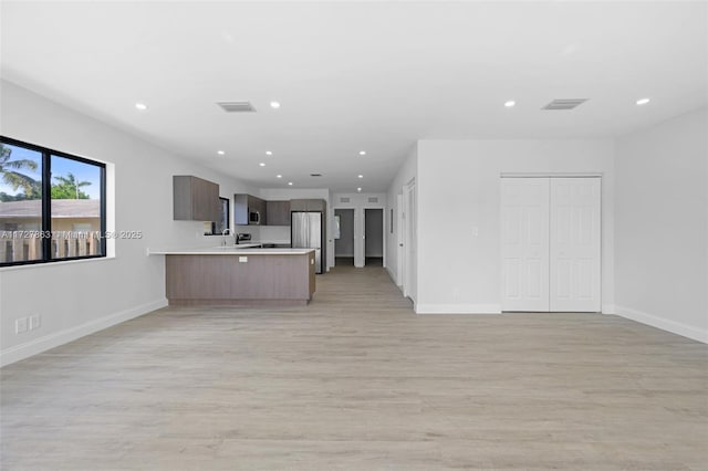 unfurnished living room featuring sink and light hardwood / wood-style floors