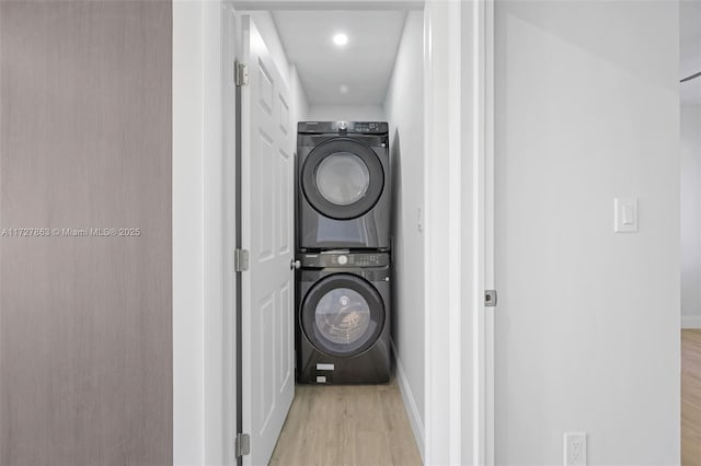 laundry room with stacked washer and clothes dryer and light hardwood / wood-style floors