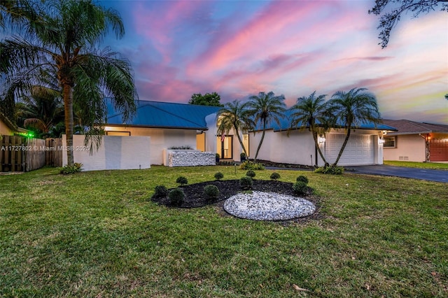 single story home featuring a garage and a lawn