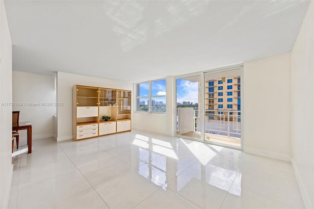 spare room featuring light tile patterned flooring, a city view, and baseboards