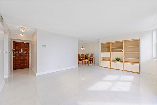 empty room with built in shelves and light tile patterned flooring