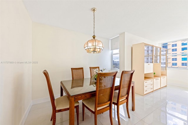 430 Golden Isles Dr Unit 707, Hallandale Beach, FL 33009 - dining space featuring a chandelier, plenty of natural light, light tile patterned flooring, and baseboards