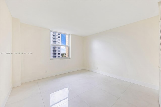 tiled spare room featuring baseboards