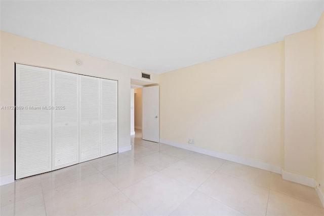 unfurnished bedroom with light tile patterned floors, baseboards, visible vents, and a closet