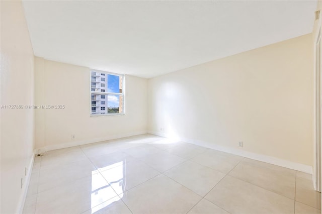 unfurnished room featuring baseboards and light tile patterned flooring