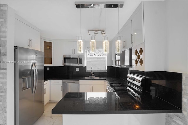 kitchen featuring pendant lighting, kitchen peninsula, decorative backsplash, white cabinetry, and appliances with stainless steel finishes