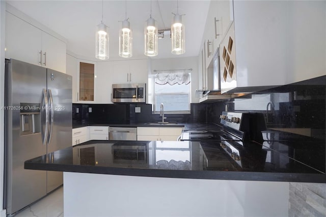 kitchen featuring kitchen peninsula, stainless steel appliances, backsplash, decorative light fixtures, and sink