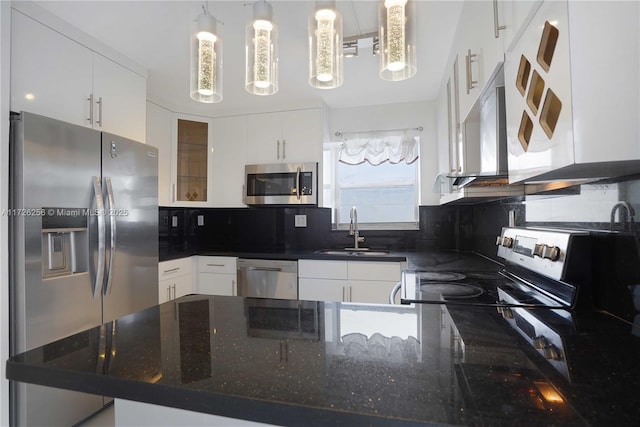 kitchen featuring stainless steel appliances, decorative light fixtures, dark stone counters, white cabinets, and sink