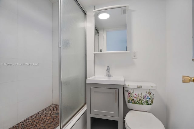 bathroom with toilet, vanity, and a shower with shower door