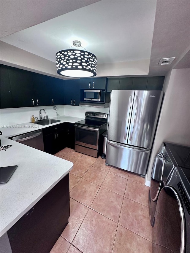 kitchen with light tile patterned floors, sink, appliances with stainless steel finishes, and washing machine and clothes dryer