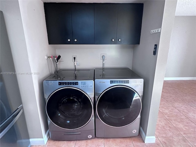 laundry area featuring washer and clothes dryer, cabinets, and light tile patterned floors