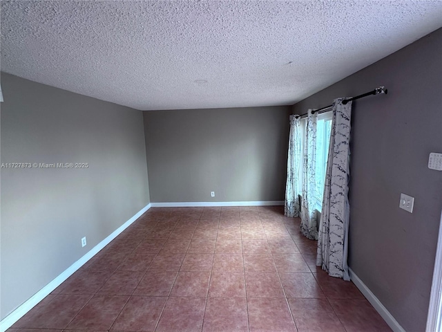 tiled empty room featuring a textured ceiling