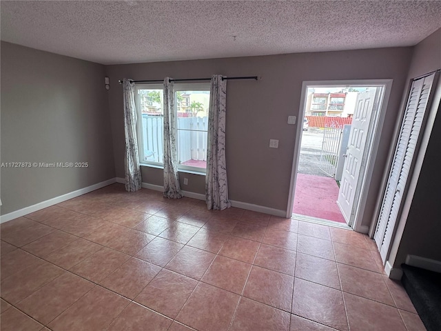 empty room with a textured ceiling and light tile patterned floors