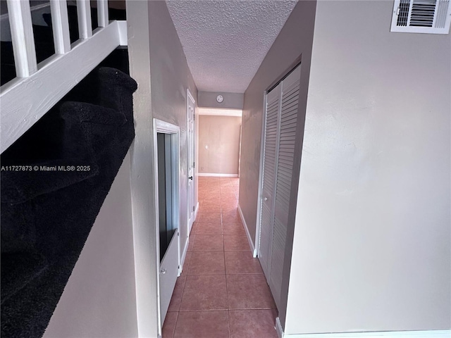 hall featuring light tile patterned flooring and a textured ceiling