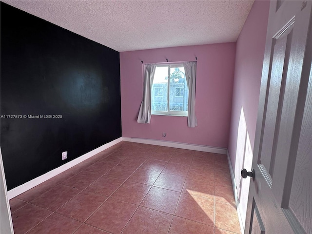 spare room with light tile patterned floors and a textured ceiling