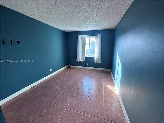 spare room with a textured ceiling and tile patterned flooring