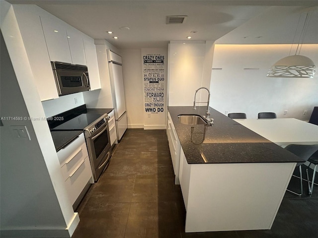 kitchen featuring decorative light fixtures, white cabinetry, sink, a kitchen island with sink, and stainless steel appliances