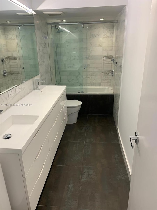 full bathroom featuring vanity, shower / bath combination with glass door, and toilet