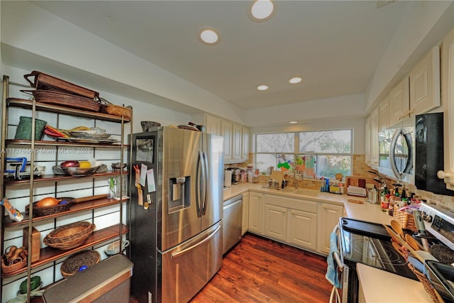 kitchen with dark wood-type flooring, appliances with stainless steel finishes, white cabinets, and sink