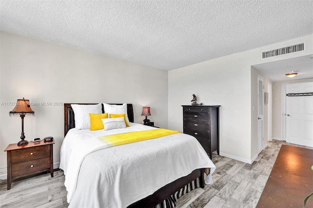 bedroom featuring a textured ceiling and light hardwood / wood-style flooring