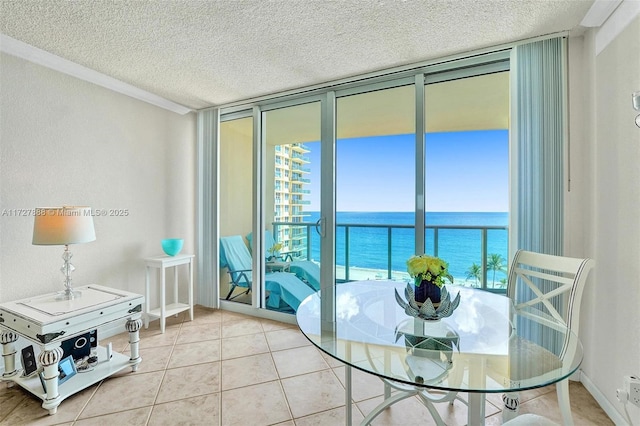 dining space featuring a textured ceiling, tile patterned flooring, a wall of windows, and a water view