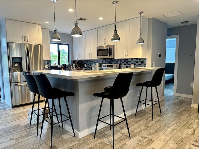 kitchen with tasteful backsplash, a breakfast bar area, stainless steel appliances, and white cabinets