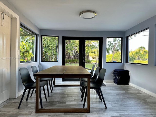 dining space with hardwood / wood-style floors, french doors, and a healthy amount of sunlight