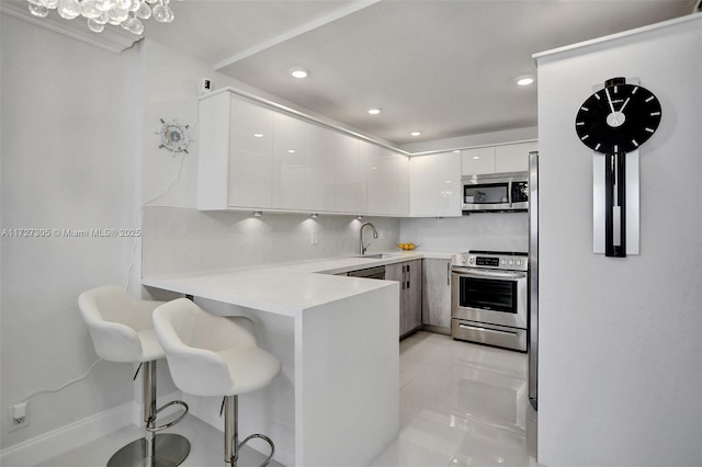 kitchen featuring sink, a breakfast bar area, white cabinets, kitchen peninsula, and stainless steel appliances