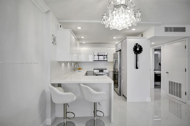 kitchen featuring appliances with stainless steel finishes, white cabinetry, sink, hanging light fixtures, and kitchen peninsula