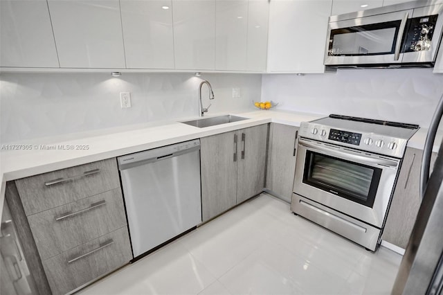 kitchen with appliances with stainless steel finishes, sink, gray cabinetry, and light tile patterned floors