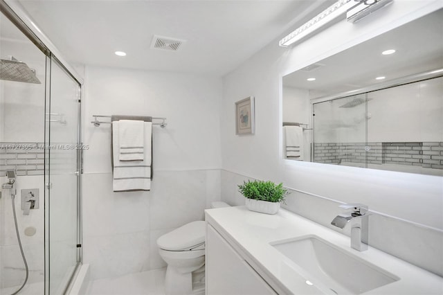 bathroom featuring a shower with door, vanity, and toilet