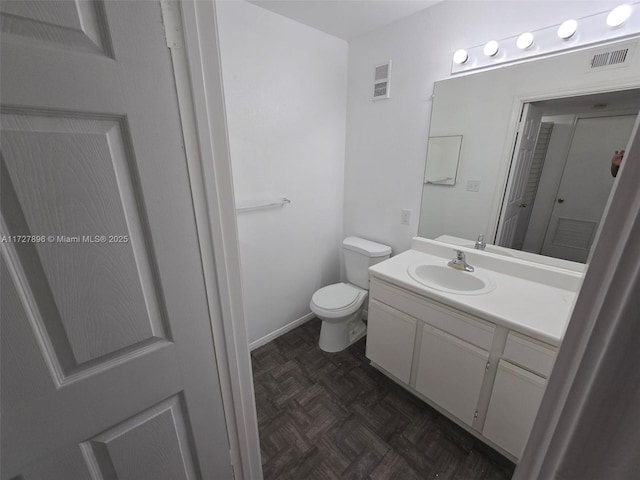 bathroom featuring parquet flooring, toilet, and vanity