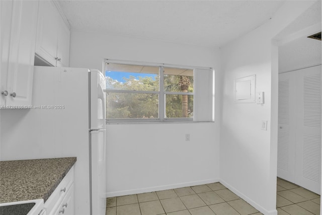 kitchen featuring white cabinetry, light tile patterned floors, stove, and white fridge