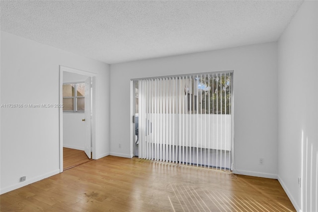 empty room featuring a textured ceiling and light hardwood / wood-style flooring