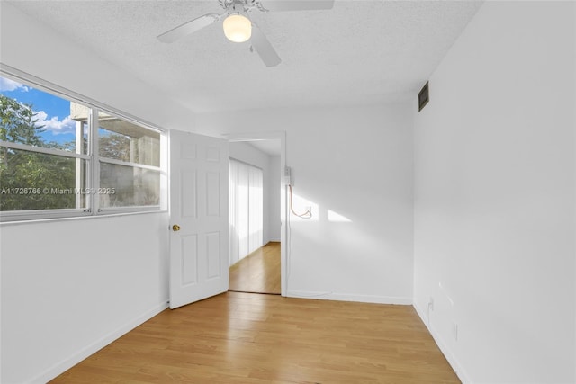 unfurnished room with ceiling fan, a textured ceiling, and light wood-type flooring