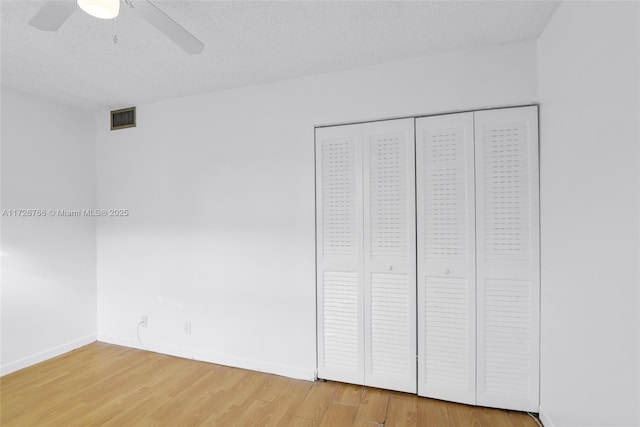 unfurnished bedroom featuring ceiling fan, wood-type flooring, a closet, and a textured ceiling