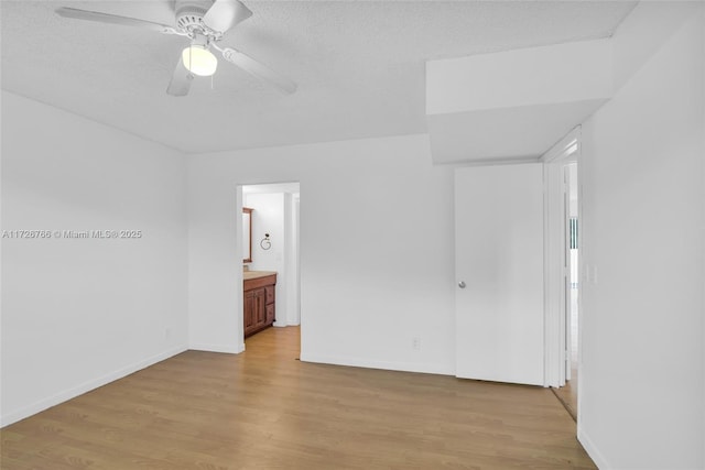 unfurnished bedroom featuring light wood-type flooring, ceiling fan, ensuite bathroom, and a textured ceiling