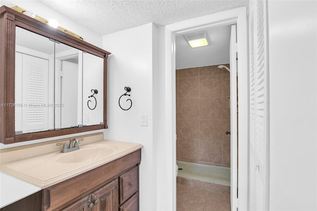 bathroom featuring vanity, tile patterned flooring, a textured ceiling, and tiled shower