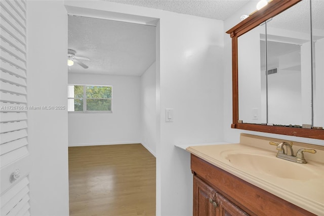 bathroom with ceiling fan, a textured ceiling, hardwood / wood-style flooring, and vanity