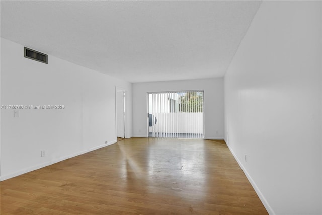 empty room with a textured ceiling and light hardwood / wood-style floors