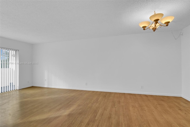 unfurnished room with light hardwood / wood-style floors, a textured ceiling, and a chandelier