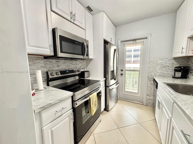 kitchen featuring appliances with stainless steel finishes, decorative backsplash, and white cabinetry