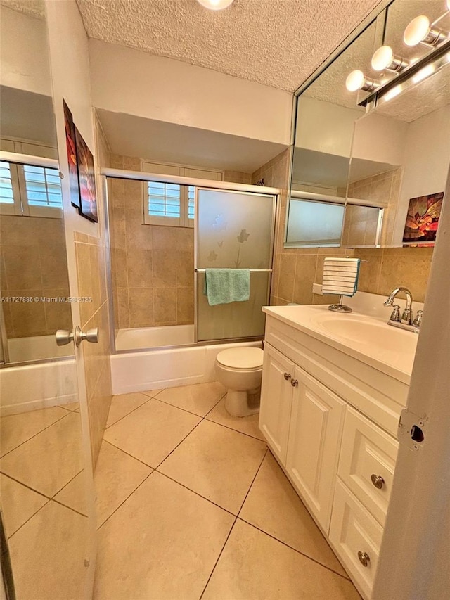 full bathroom featuring toilet, vanity, tile patterned floors, enclosed tub / shower combo, and a textured ceiling