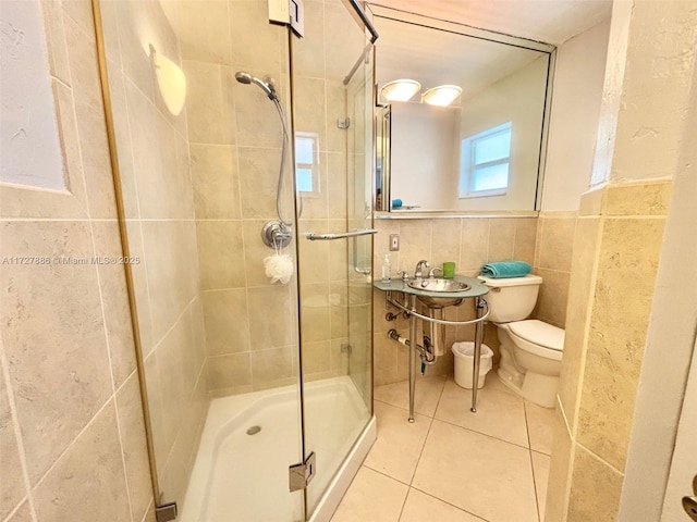 bathroom with toilet, tile walls, tile patterned floors, sink, and an enclosed shower