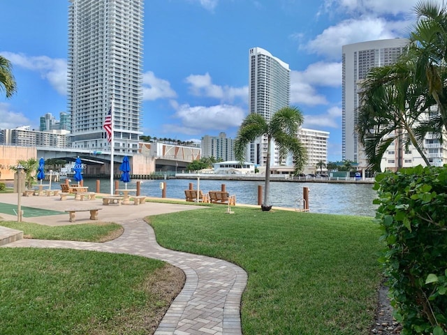 surrounding community with a water view and a lawn