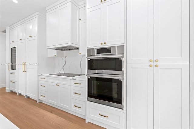 kitchen with white cabinetry, double oven, light hardwood / wood-style floors, backsplash, and black electric cooktop